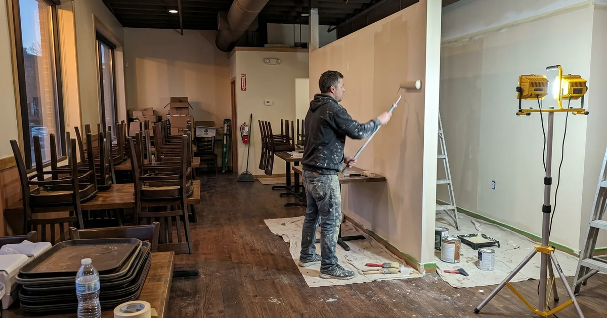 Round Rock restaurant dining room after close with chairs stacked on tables and a painter at work