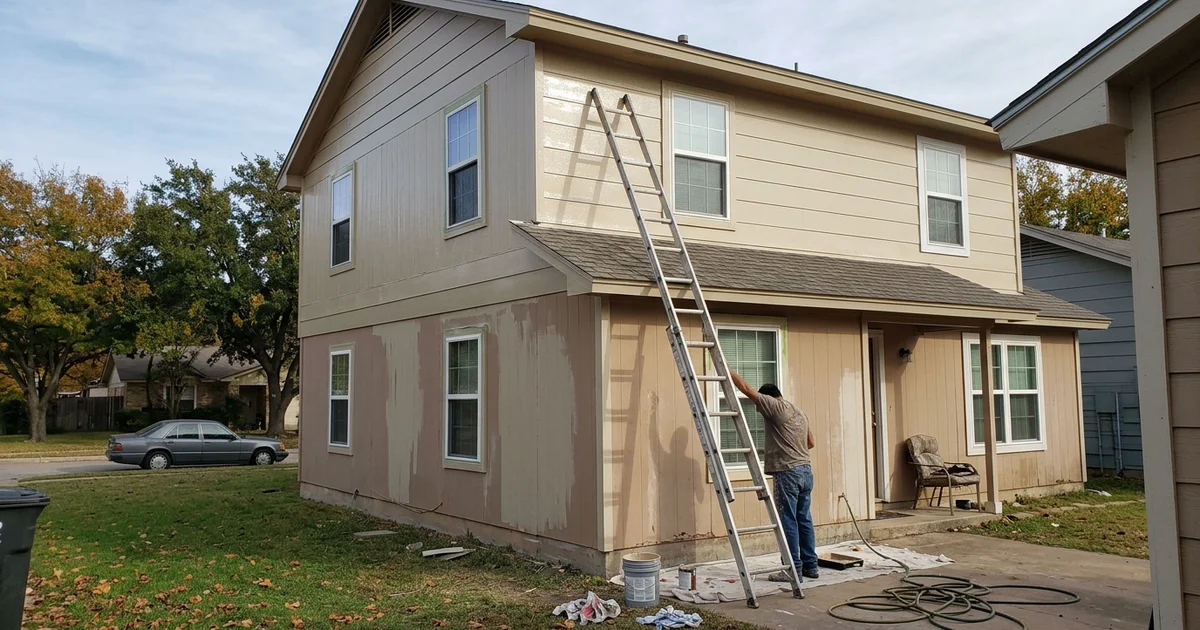 Two-story Round Rock fiber cement house mid-repaint with a ladder against the wall on a fall morning