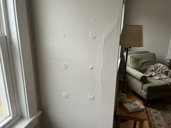 Before: Round Rock living room wall with nail pops and a cracked tape joint
