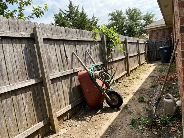 Before: sun-grayed cedar fence with weathered boards