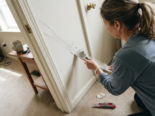 Taping a diagonal settlement crack at a door corner in a Round Rock home