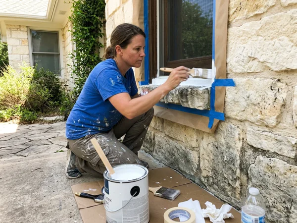 Masking natural limestone on a Round Rock home while cutting in exterior trim